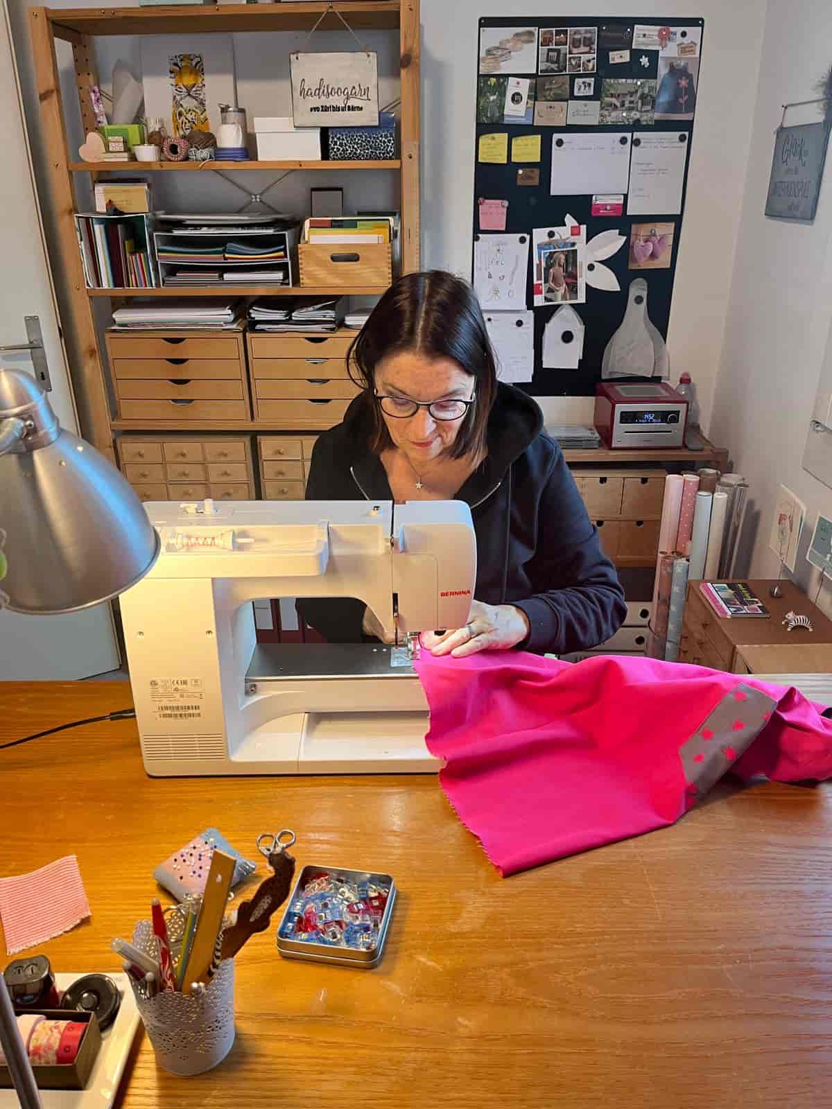 Doris Brignoli näht an ihrer Nähmaschine an einem pinken Stoff
