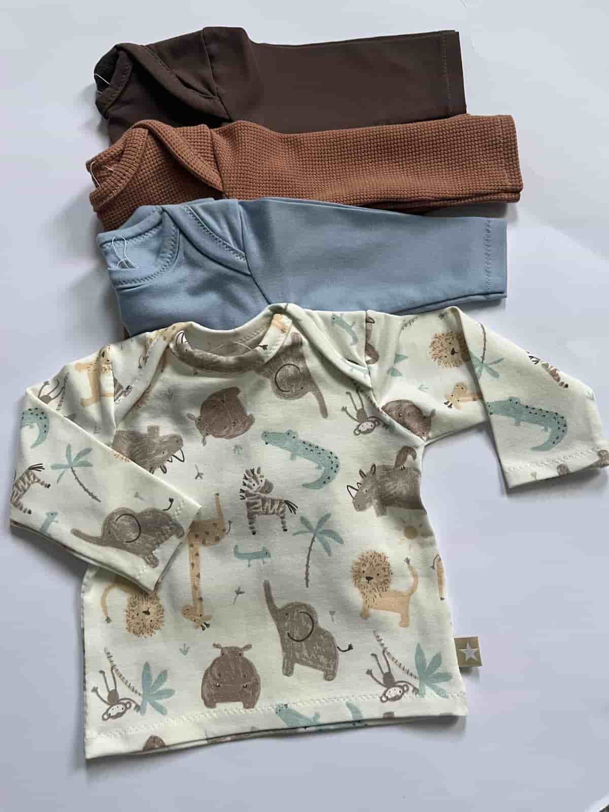 Drei Baby-Shirts in Braun, Blau und mit Dschungeltier-Muster